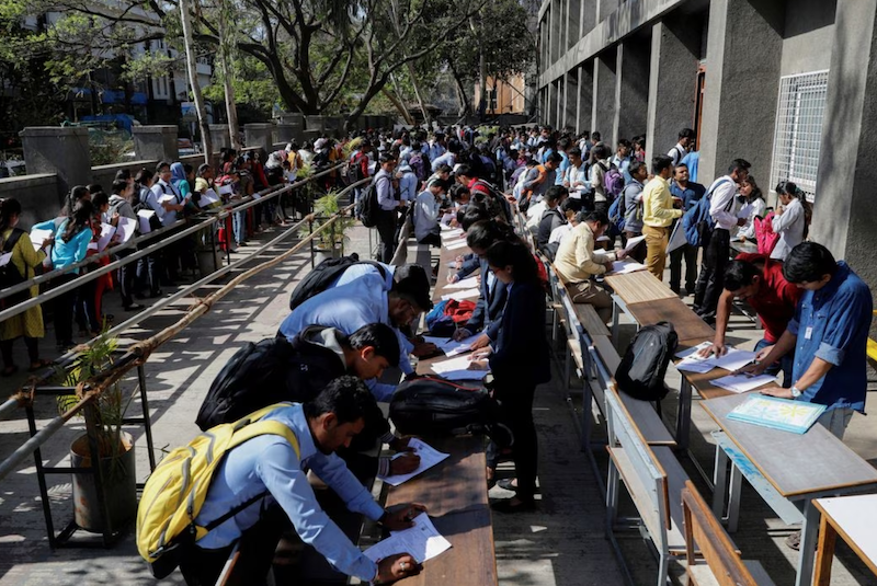 Job seekers fill up forms as others line up for registration during a job fair in Chinchwad, India, February 7, 2019. REUTERS/Danish Siddiqui