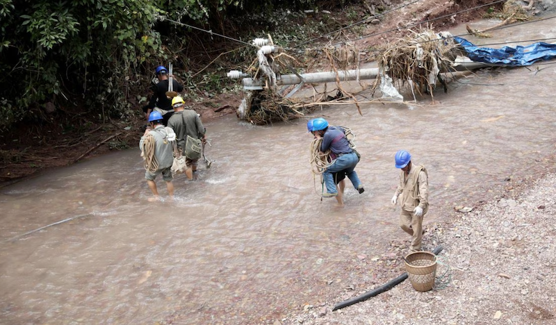 Electrical workers wade through waters next to a damaged power pole in Haogenping village, after heavy rainfall lashed Guzhang county in Xiangxi Tujia and Miao autonomous prefecture, Hunan province, China July 2, 2023. China Daily via REUTERS