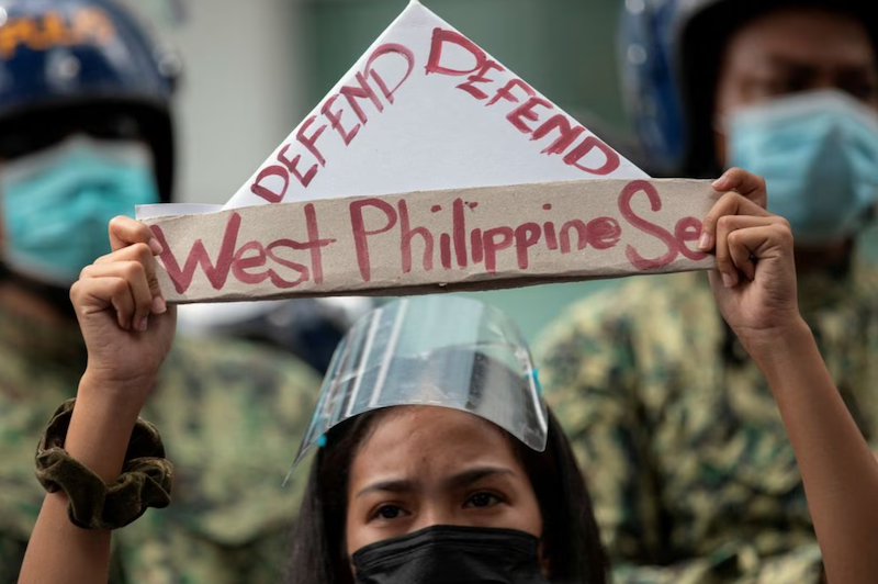 An activist holds a prop with the words "defend West Philippine Sea" during a protest outside the Chinese Consulate in Manila's financial district, guarded by Philippine police, on the anniversary of an international arbitral court ruling invalidating Beijing's historical claims over the waters of the South China Sea, in Makati City, Philippines, July 12, 2021. REUTERS/Eloisa Lopez/File Photo