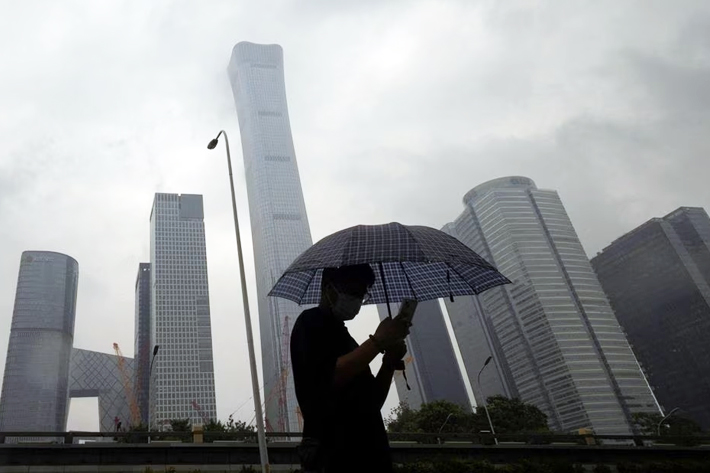 A man walks in the Central Business District on a rainy day, in Beijing, China