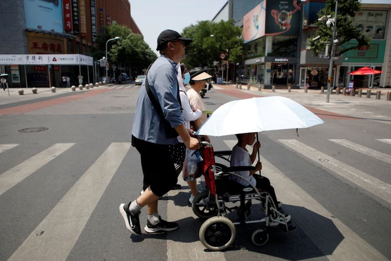 Pedestrians cross a road on a hot day amid an orange alert for heatwave, in Beijing, China June 16, 2023. REUTERS/Florence Lo/File Photo