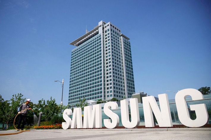 A worker waters a flower bed next to the logo of Samsung Electronics during a media tour at Samsung Electronics' headquarters