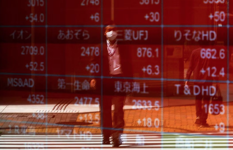 A man is reflected on an electric stock quotation board outside a brokerage in Tokyo, Japan April 18, 2023. REUTERS/Issei Kato