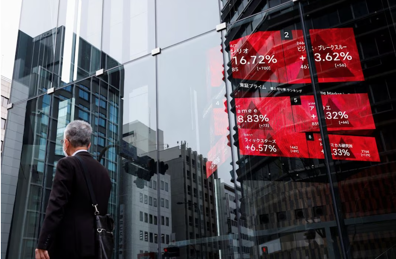 A man walks past an electronic board showing stock visualizations outside a brokerage, in Tokyo, Japan, March 17, 2023. REUTERS/Androniki Christodoulou Acquire Licensing Rights