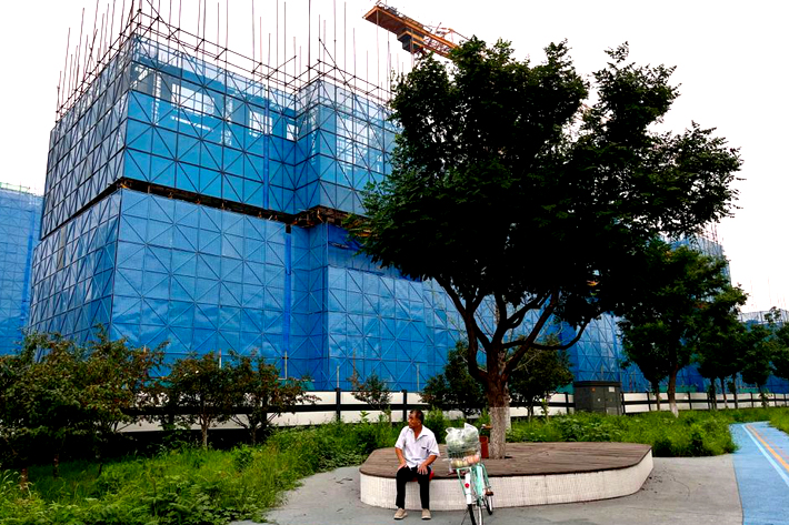 A person sits near a construction site of residential buildings by Chinese developer Country Garden, in Beijing, China