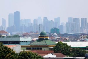 Mosques are seen in a residential area, as smog covers high-rise buildings in the background, in Jakarta, Indonesia