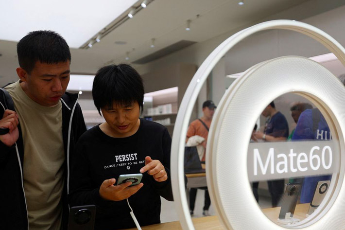 People check a Huawei Mate 60 smartphone displayed at a Huawei flagship store in Beijing, China