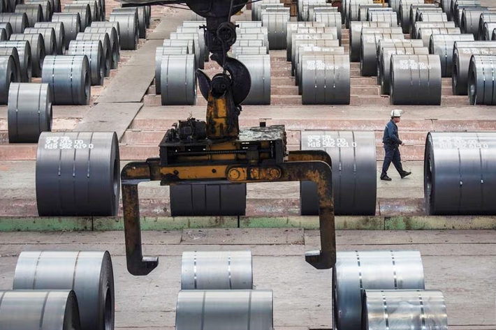 A worker walks past steel rolls at the Chongqing Iron and Steel plant in Changshou, Chongqing, China