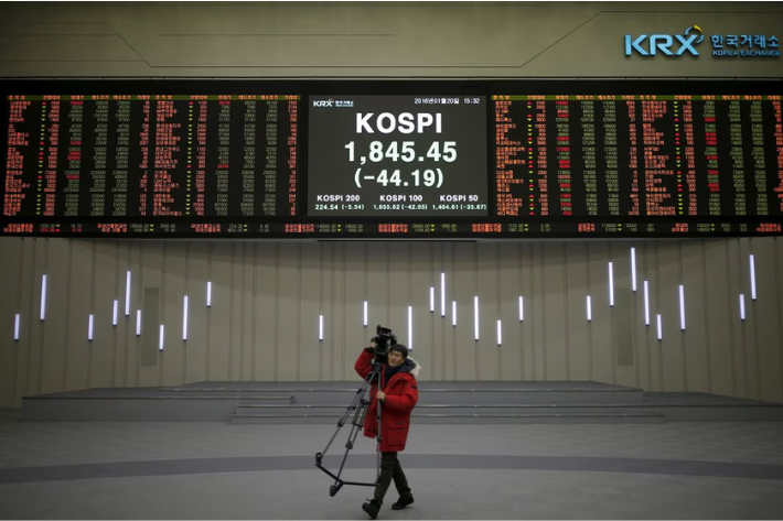 A journalist walks past an electronic board of the Korea Composite Stock Price Index (KOSPI) at the Korea Exchange (KRX) in Seoul, South Korea