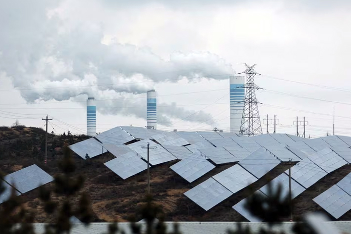 Smoke rises from chimneys near solar panels, during a Huawei-organised media tour, in Shaanxi province, China