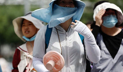 People wearing sun protection gear amid a heatwave walk on a street in Beijing, China July 1, 2023. Photo: Reuters