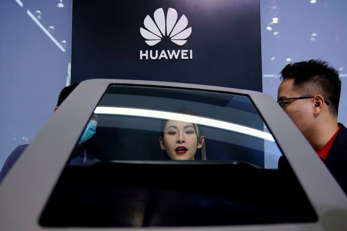 People check a display near a Huawei logo during a media day for the Auto Shanghai show in Shanghai, China