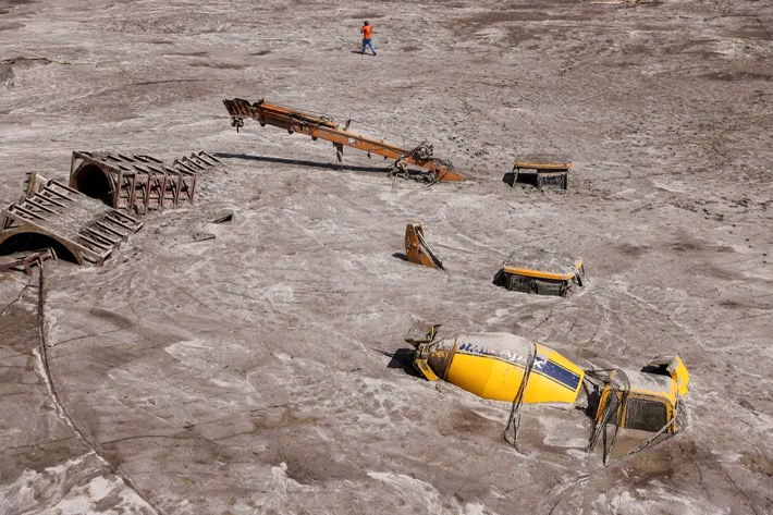 A man walks past construction vehicles covered in debris caused by flash floods after a lake burst in Rangpo, Sikkim state, India