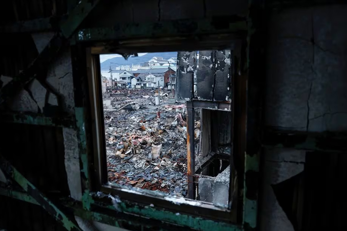 Debris accumulates along Asaichi-dori street, which burned down due to a fire following an earthquake, as seen from a window hole, in Wajima, Japan