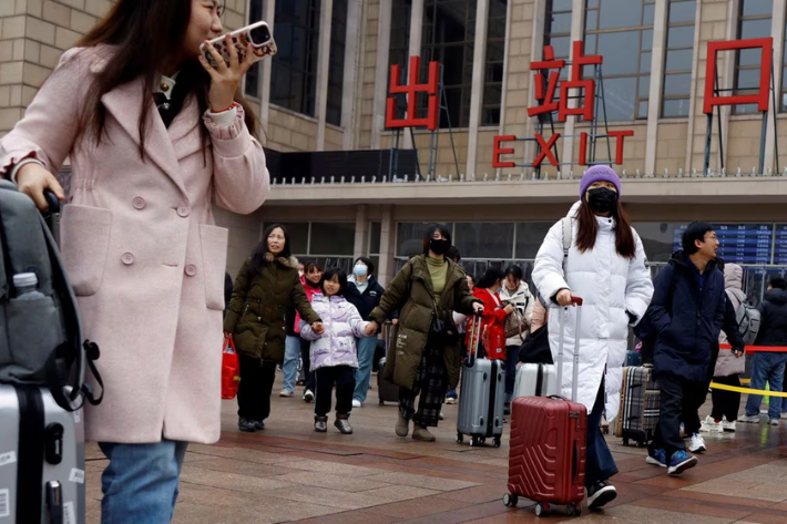 Travellers walk with their luggage outside the Beijing railway station during the Spring Festival travel rush following the eight-day Lunar New Year holiday, in Beijing, China