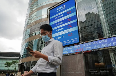 People walk past a screen displaying the Hang Seng stock index outside Hong Kong Exchanges, in Hong Kong, China, on July 19, 2022. Photo: Reuters