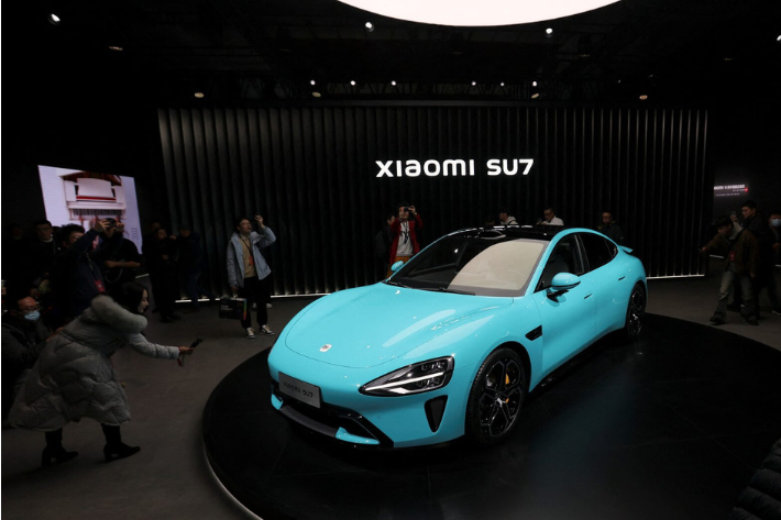 Visitors film around Xiaomi's first electric vehicle, the SU7, displayed at an event in Beijing, China