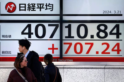 Passersby walk in front of an electric screen displaying Japan's Nikkei share average outside a brokerage in Tokyo, Japan, on March 21, 2024. Photo: Reuters