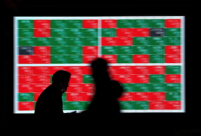 Passersby walk past an electric stock quotation board outside a brokerage in Tokyo. Photo: Reuters