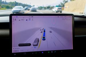 A Tesla Model 3 vehicle warns the driver to keep their hands on the wheel and be prepared to take over at anytime while driving using FSD (Full Self-Driving) in Encinitas, California, US