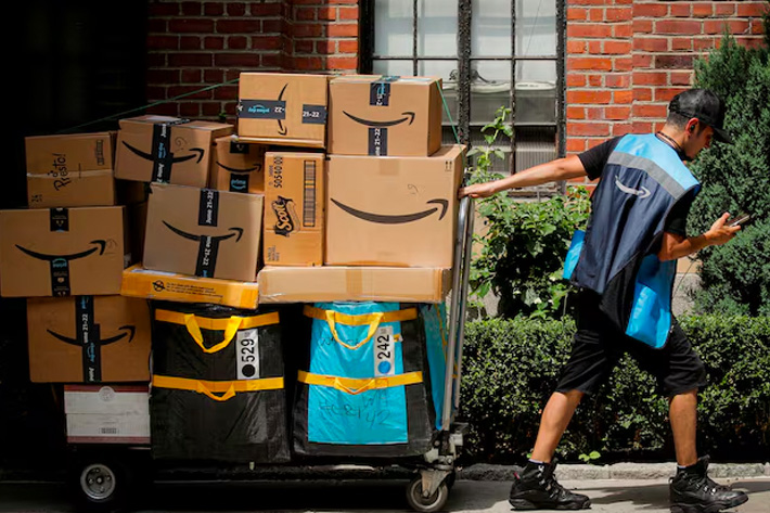 An Amazon delivery worker pulls a delivery cart full of packages during its annual Prime Day promotion in New York City, US
