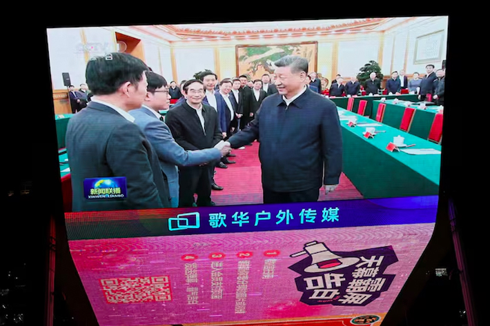 A giant screen shows news footage of Chinese President Xi Jinping shaking hands with DeepSeek founder Liang Wenfeng during a symposium on private enterprises, at a shopping complex in Beijing, China.