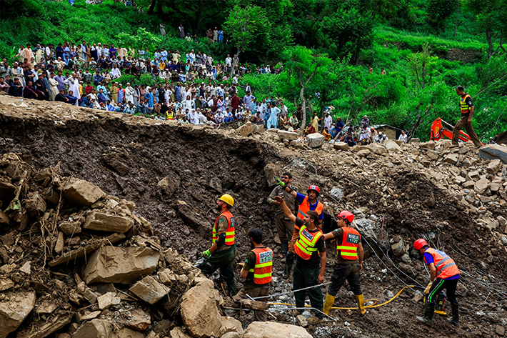 Residents gather as rescue workers look for victims, following a storm that caused heavy rains and flooding in Dalori Bala village in Gadoon district in Khyber Pakhtunkhwa